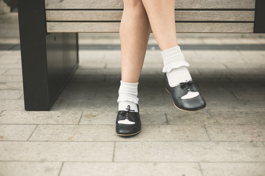 Feet of young woman relaxing on bench in city