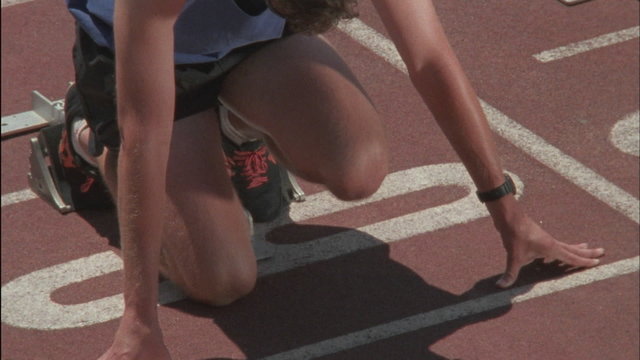 A runner kneels at the starting point, then starts to race.