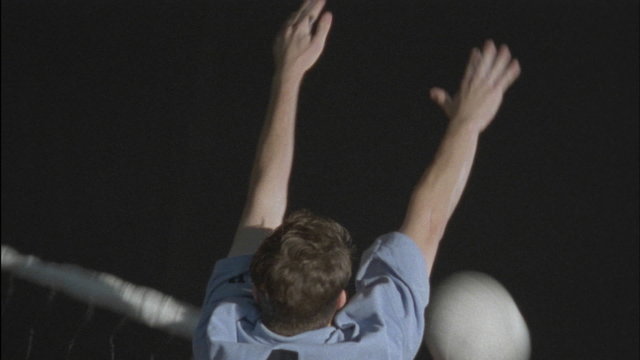 A volleyball is thrown back and forth across a net.