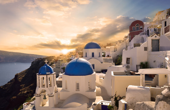 Fototapeta Traditional white architecture in Oia Santorini, illuminated by a beautiful sunset in Greece - Europe