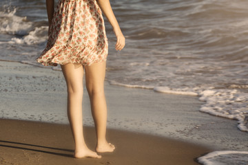 The legs of a woman walking on a beach