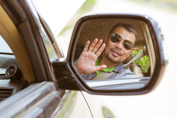 Naklejka premium Asian man show his hand looking from car's mirror