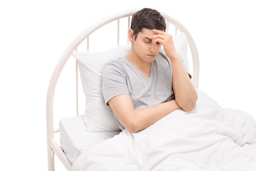 Man in bed experiencing a severe headache