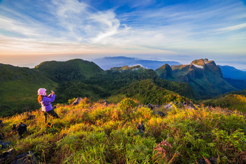 Obraz premium young woman take photographs during Sunset on mountain with landscape view