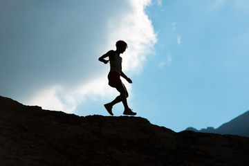 Woman runs downhill on mountain trail