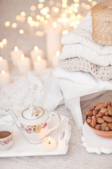 Warm white wool sweaters on white wood stool with candles and te