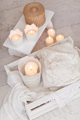 Warm white wool sweaters on white wood stool with candles and te