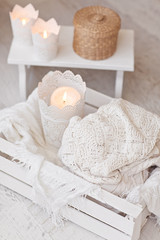 Fototapeta na wymiar Warm white wool sweaters on white wood stool with candles and te
