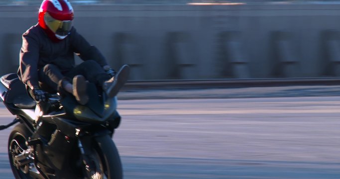 A rider performs stunts on a motorcycle in a parking lot.