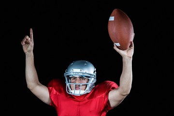 American football player with arms raised holding ball