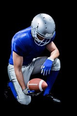 Fototapeta premium American football player kneeling while holding ball