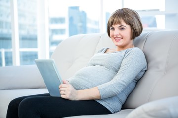 Portrait of smiling pregnant woman using digital tablet 