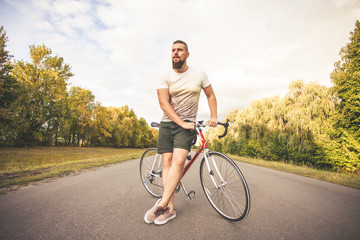 Young hipster style man posing with bicycle