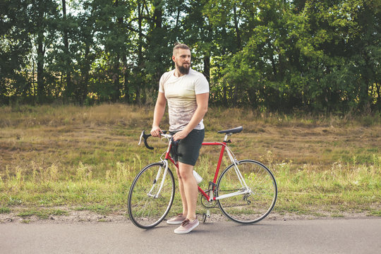 Young hipster style man posing with bicycle
