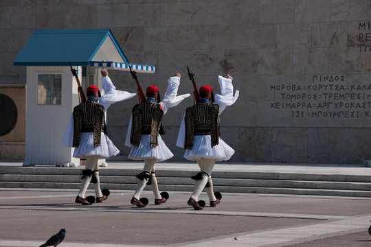 Greek guardsmen holding rifle guns march in front of the Unknown soldier monument in Syntagma, central Athens, Greece