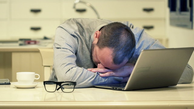 Tired businessman sleeping on table in kitchen at night