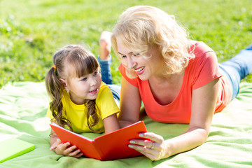 Mother with daughter in park reading book