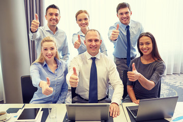 business people showing thumbs up in office