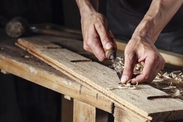 carpenter hands working with a chisel and carving tools