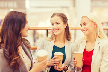 young women with shopping bags and coffee in mall