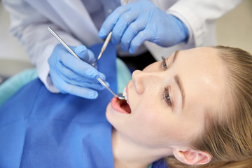 close up of dentist checking female patient teeth