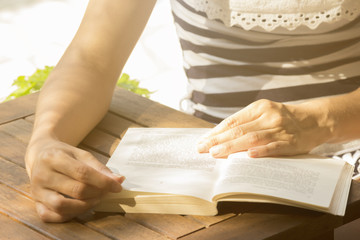 Unrecognizable young female reading a book outdoors