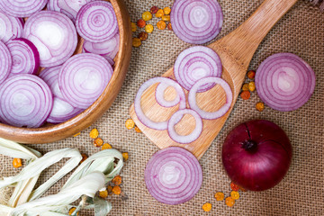 chopped red onions in wooden spoon  on sackcloth, as background