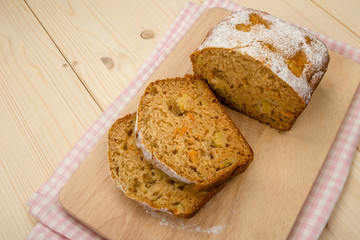 Fruit cake with two slices on a linen napkin and a light wooden