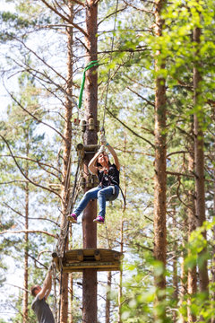 Young brave woman climbing in a adventure rope park
