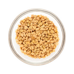 Top view of Organic Fenugreek (Trigonella foenum-graecum) half filled in glass bowl isolated on white background.