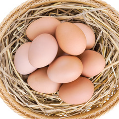 brown chicken eggs in basket with straw