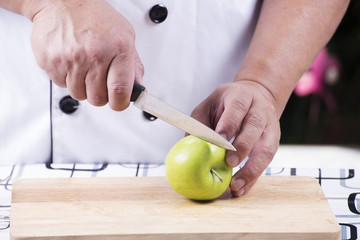 Chef's hands cutting green apple