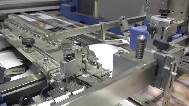 folding machine STEADYCAM folds printed offset sheet as part of newspaper brochure in print house. UHD steadycam 4K stock footage