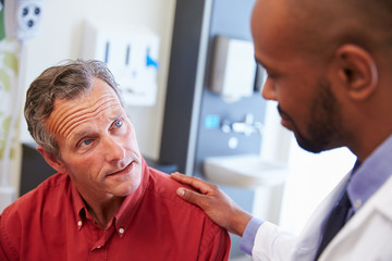 Male Patient Being Reassured By Doctor In Hospital Room