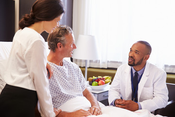 Obraz premium Doctor Talking To Male Patient And Wife In Hospital Bed