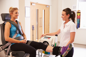 Female Patient Working With Physiotherapist In Hospital