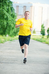 Sporty man jogging in city street park. Outdoor fitness.