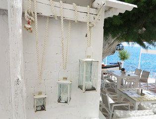 Three candle lamp decoration over white brick wall and tables ne