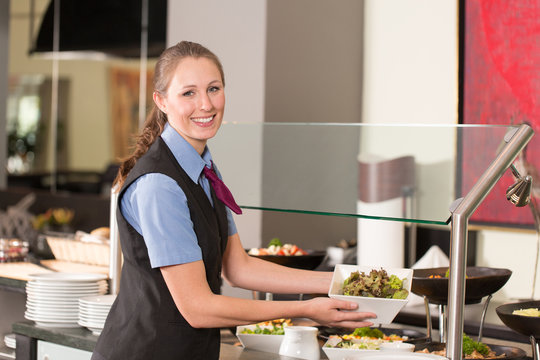 Waitress or catering professional putting food into buffet