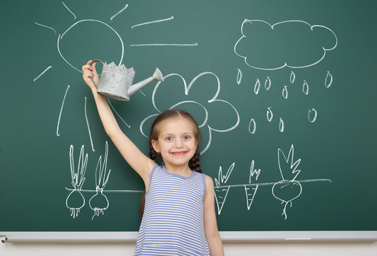 girl with watering can drawing on school board