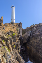 Fototapeta premium Lighthouse on the ocean against a blue sky