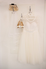 Bride dress and shoes is hanging on the hanger 