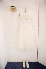 Bride dress and shoes is hanging on the hanger 