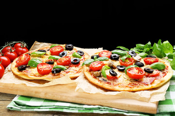Tasty pizza with vegetables and basil on black background