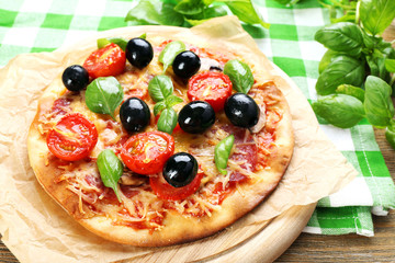 Tasty pizza with vegetables and basil on table close up