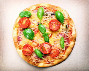 Tasty pizza with vegetables and basil in cardboard box close up