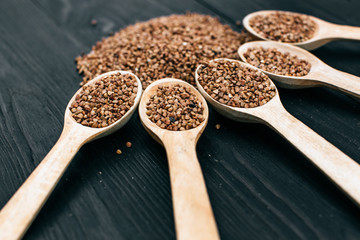 buckwheat groats and wooden spoon on the black table