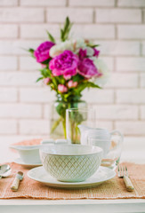 Beautiful table setting with flowers in vase on brick wall background