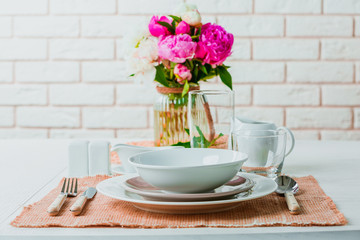 Beautiful table setting with flowers in vase on brick wall background