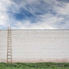 Fototapeta na wymiar Blue sky behind the huge wall with a wooden ladder